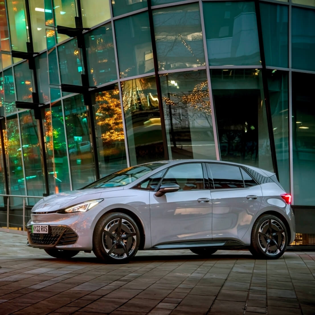 A CUPRA Born parked in front of a glass building