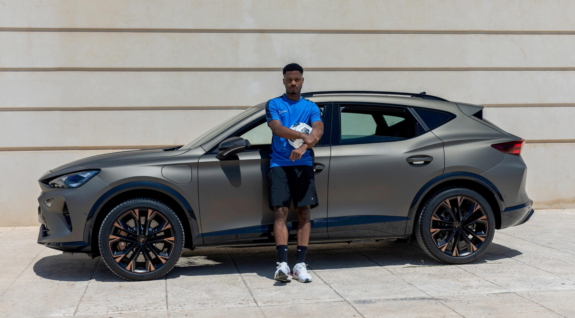 Ansu Fati standing in front of a CUPRA car