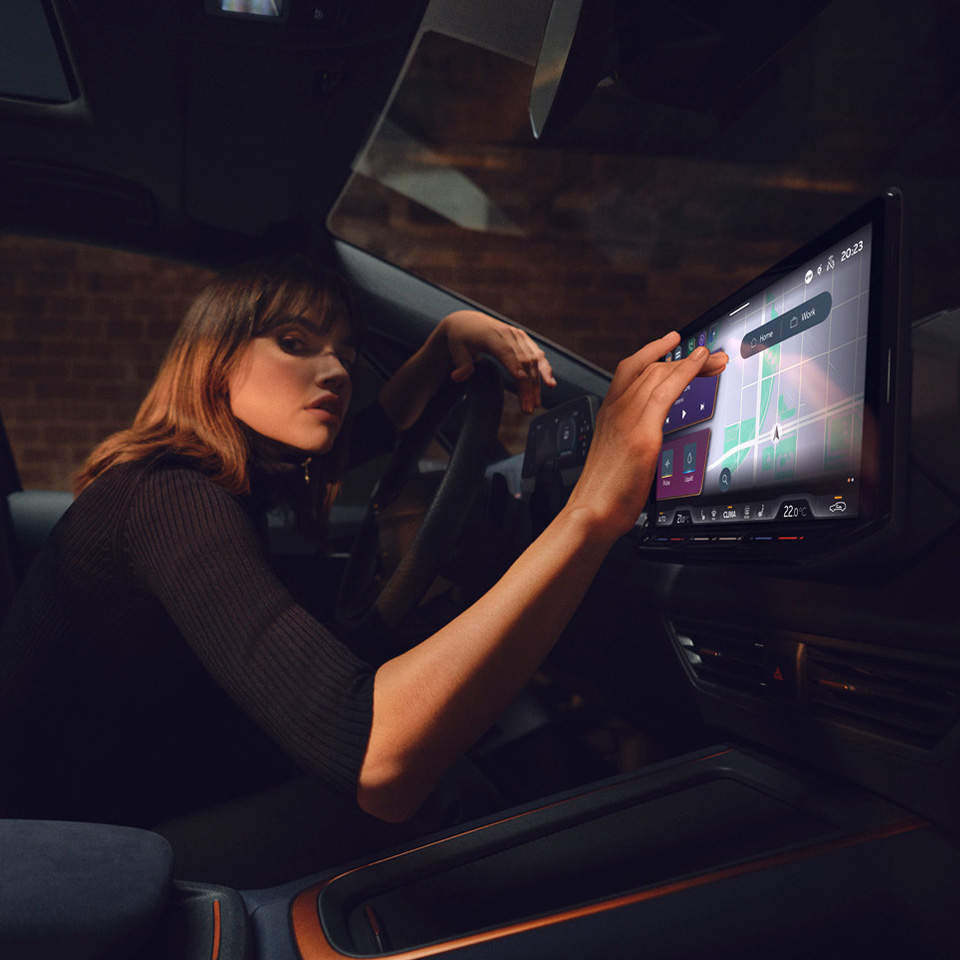 A woman sat inside a CUPRA Born V1 touching the touchscreen