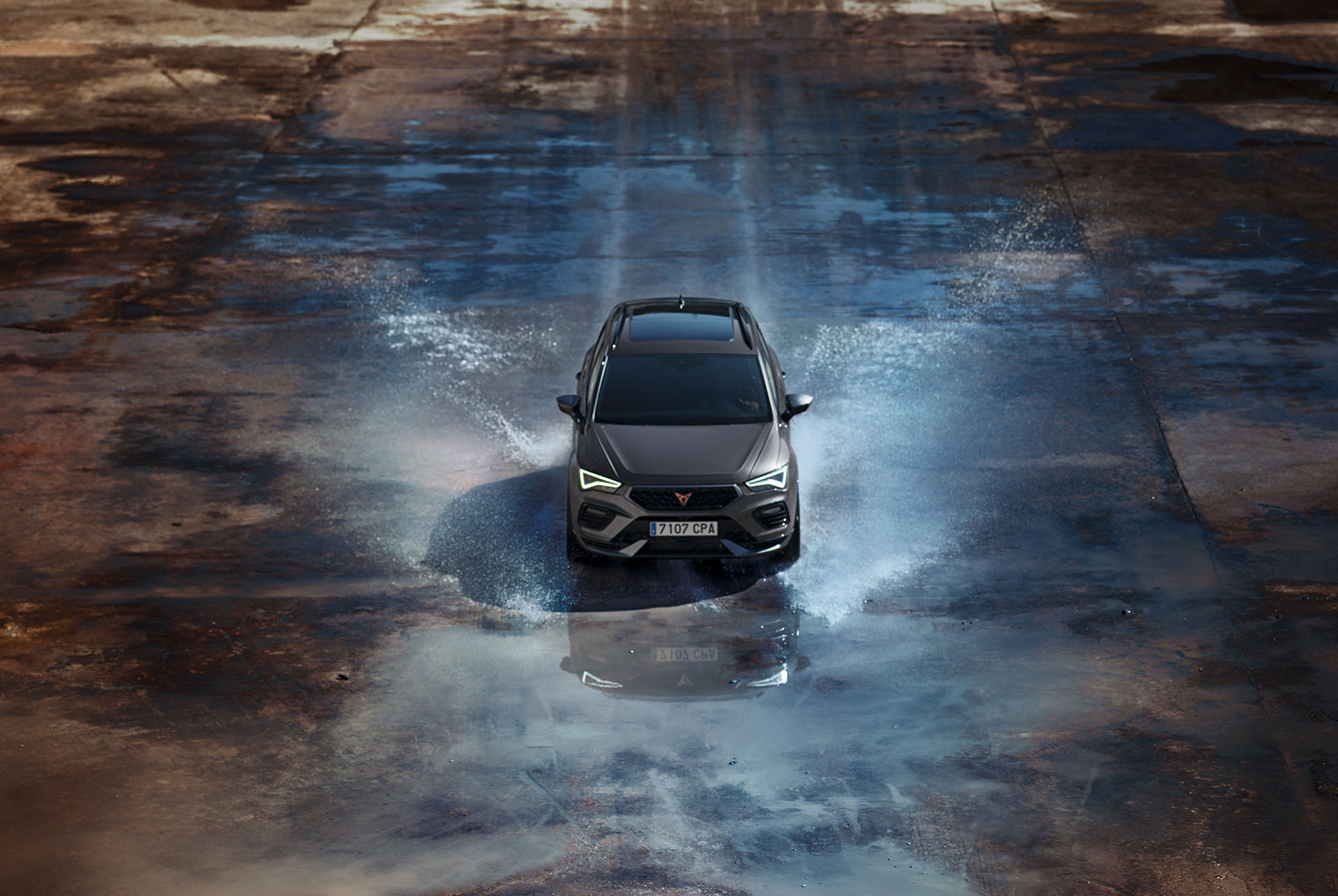 Front view of the CUPRA Ateca driving through water, showcasing its accentuated bonnet, full LED headlights, dark aluminium detailing and performance brakes with Brembo calipers.