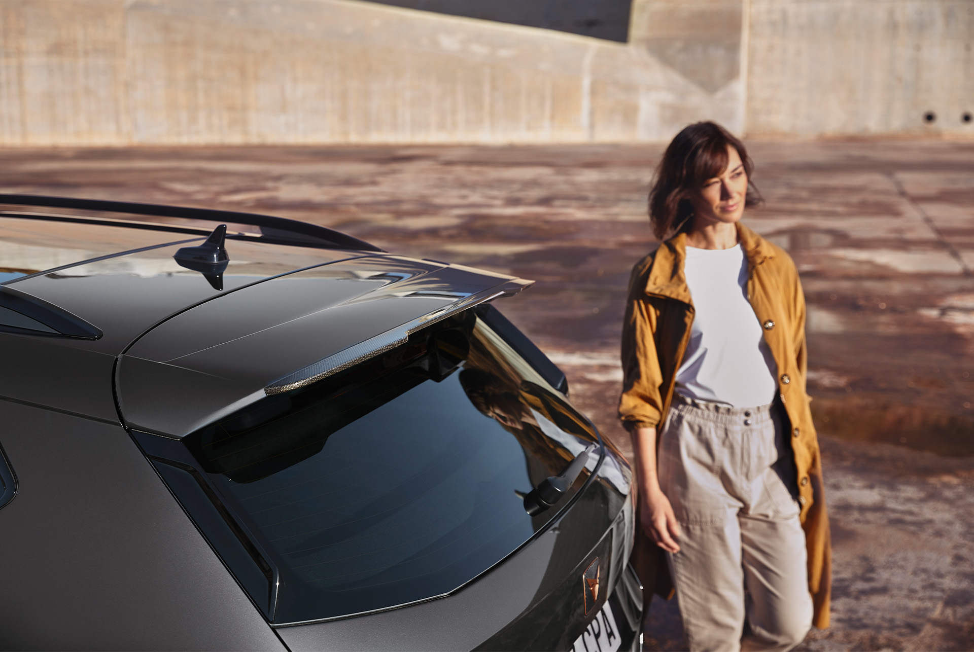 Rear view of the CUPRA Ateca with a person standing beside it, highlighting flexible monthly payment options for servicing and car maintenance.