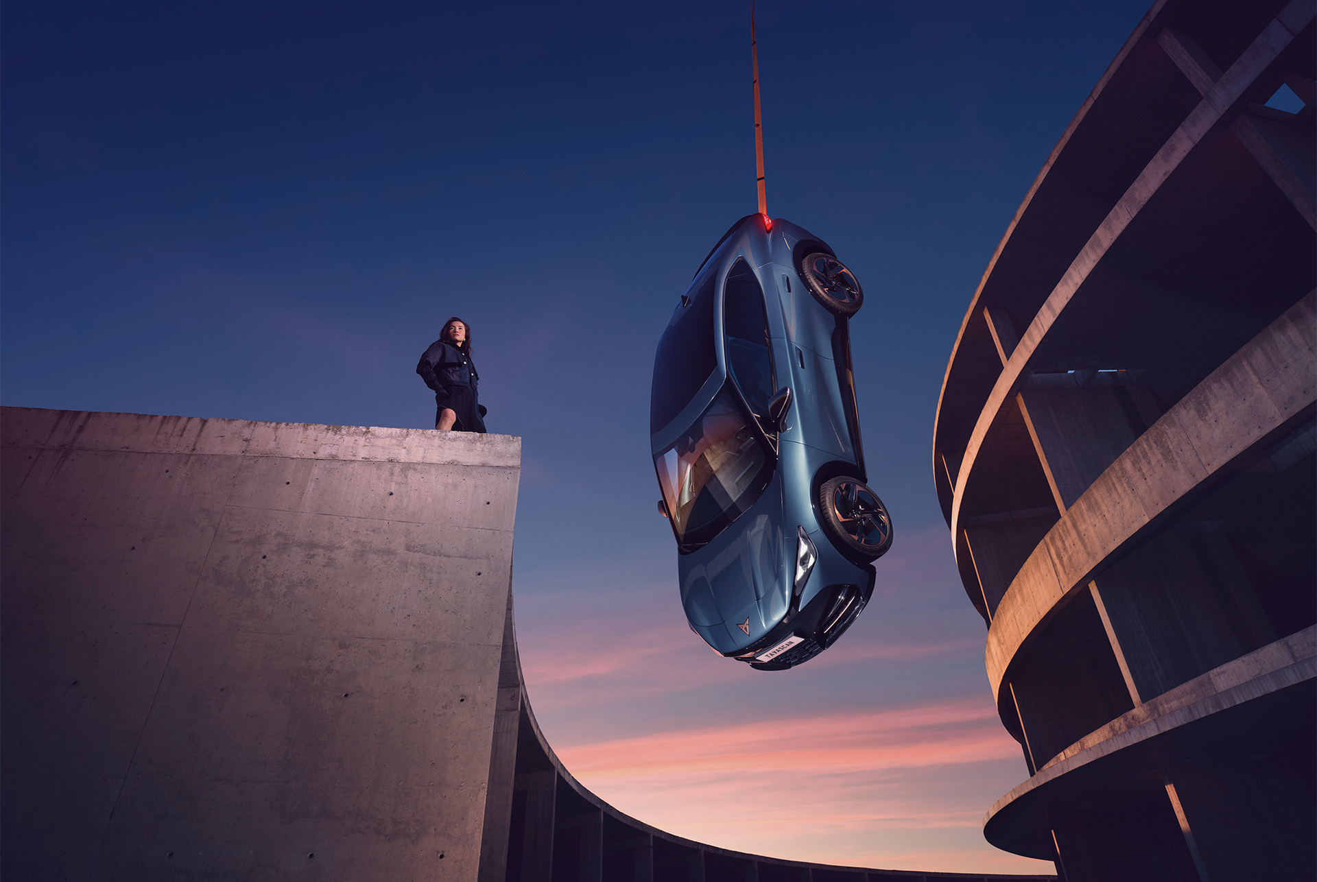 Blue CUPRA Tavascan 2024 electric SUV coupé suspended over a city skyline