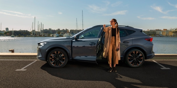 Woman standing next to a CUPRA Formentor in the sun Woman standing next to a CUPRA Formentor in the sun