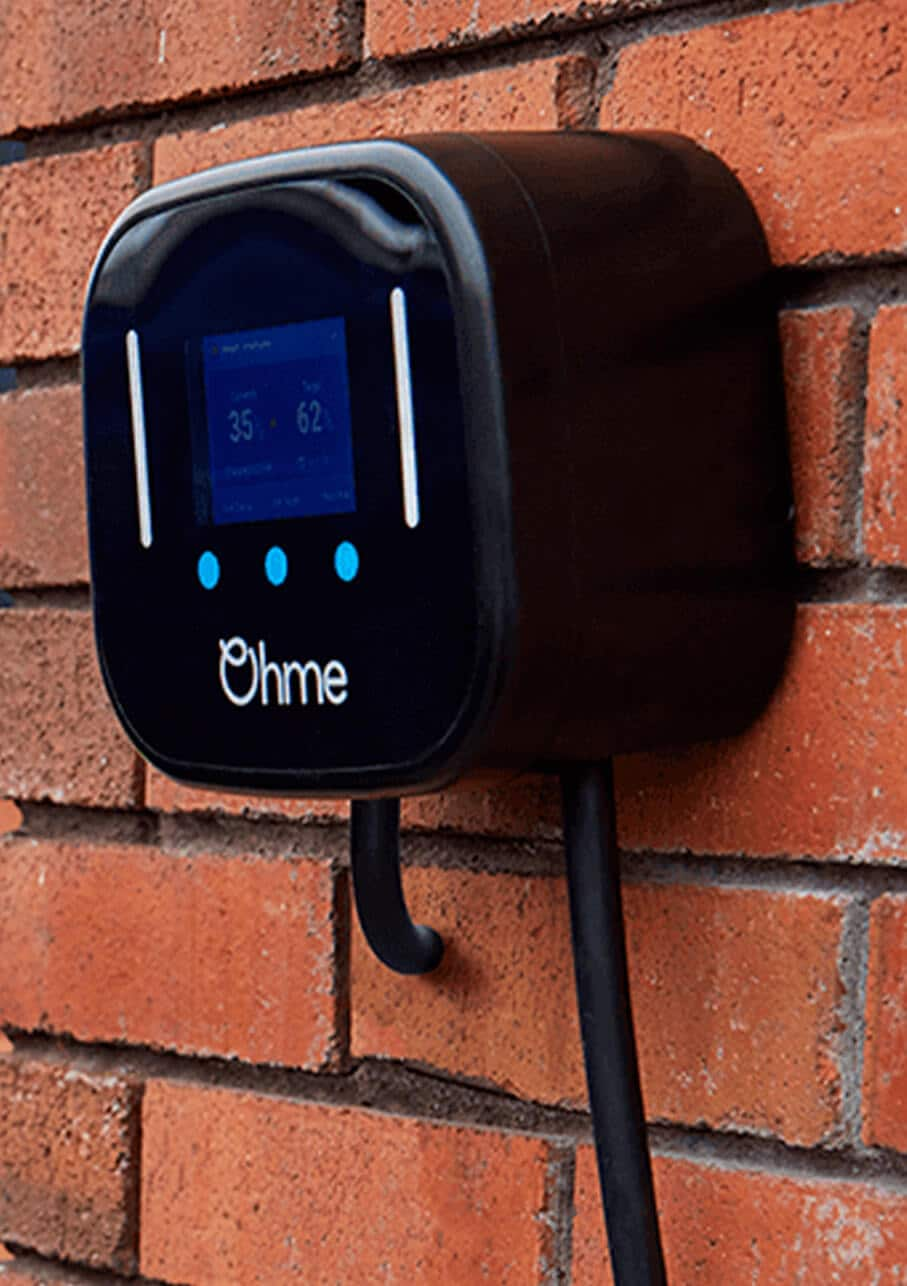 Ohme charger on brick wall with child paying in the background