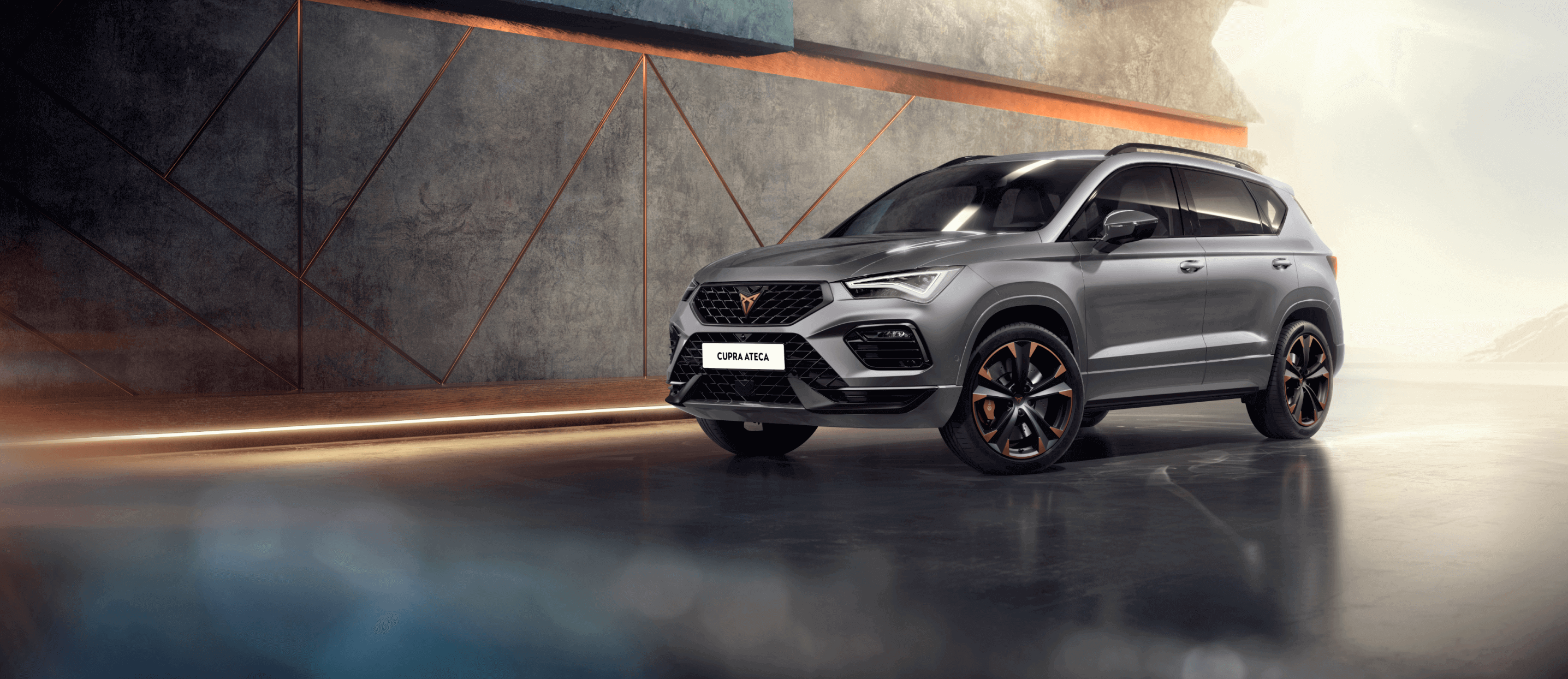 a grey CUPRA Ateca parked next to a low lit grey geometric patterned wall