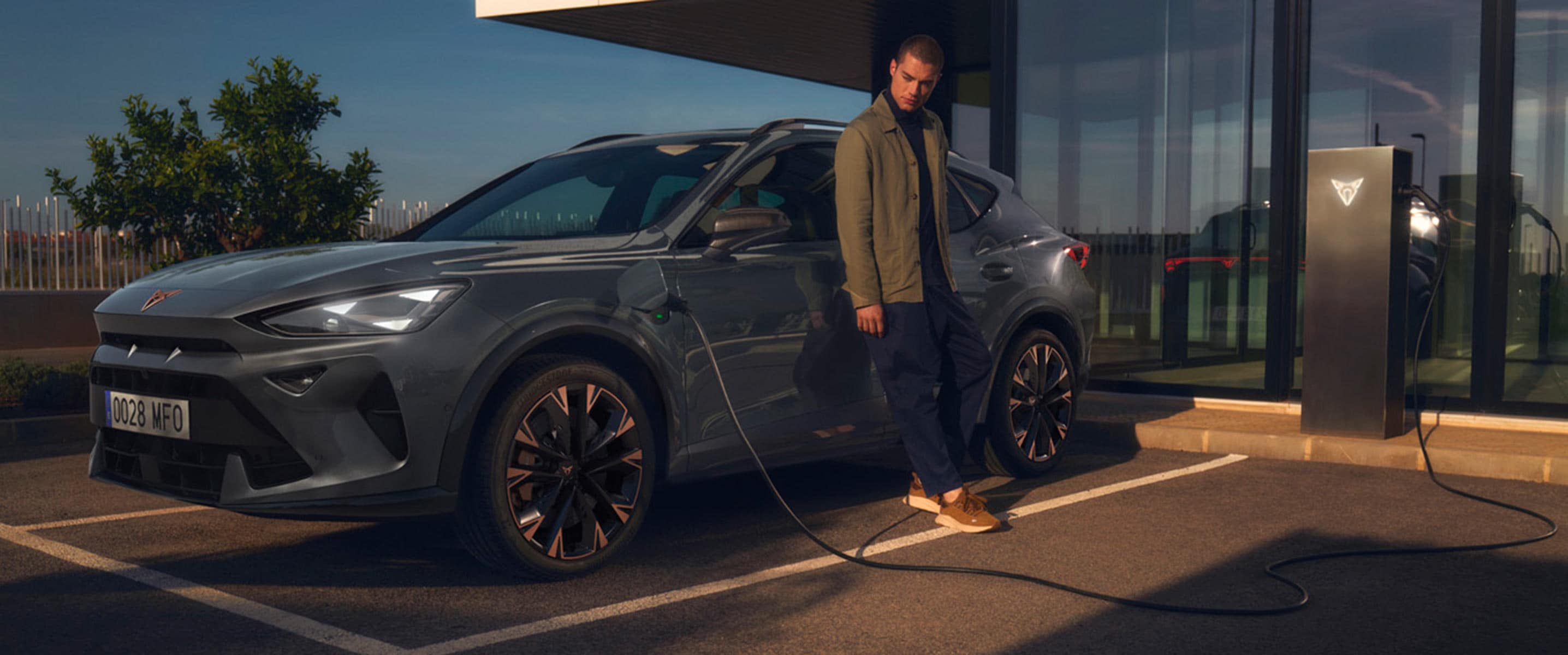 cupra formentor phev at public charging point with owner standing next to the hybrid car